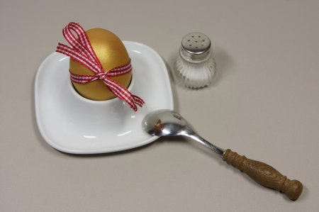 golden egg in an egg cup and spoon loop