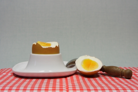 golden egg in an egg cup on a red patterned napkin with spoon
