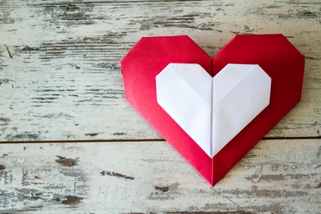 Red and white origami hearts on white wooden tableの写真素材