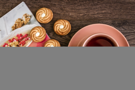 Cup of tea in pink mug and biscuits with magazineの写真素材
