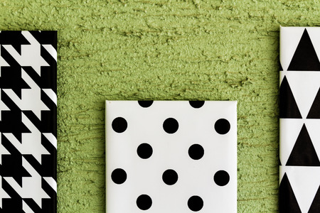 Black and white geometrical painted canvases hanging on green wallの写真素材
