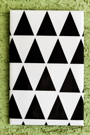 Black and white geometrical painted canvases hanging on green wall