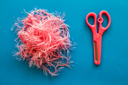 Pink toy scissors and fabric on blue paper backgroundの写真素材