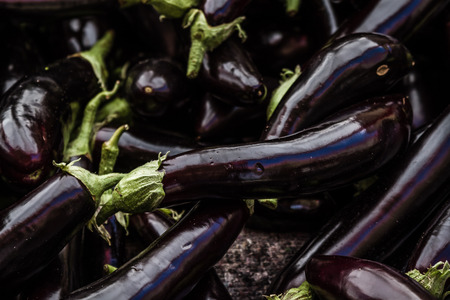 Group of fresh eggplants on a counter in an open marketplaceの写真素材