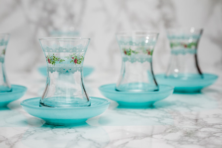 Traditional green Turkish tea glasses and plates on white marble backgroundの写真素材