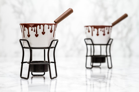 Decorative chocolate fondue bowls and sticks on white marble backgroundの写真素材