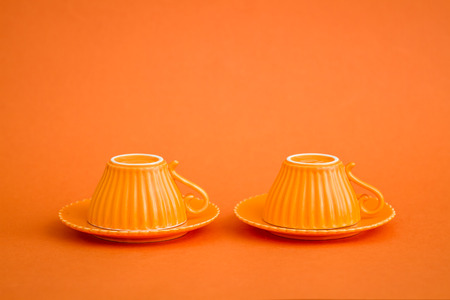 Cute colorful coffee cups on orange background with copy spaceの写真素材