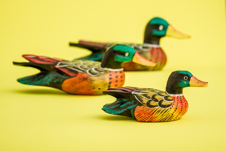 Hand made wooden ducks for home decoration on yellow backgroundの写真素材