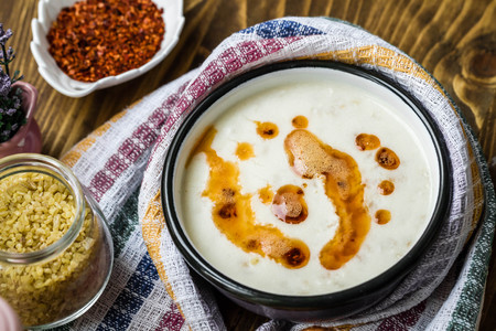 Traditional Turkish tarhana soup in an enamel bowl on brown wooden tableの写真素材