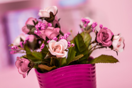 Artificial pink flowers in pink flowerpot on pink wooden backgroundの写真素材