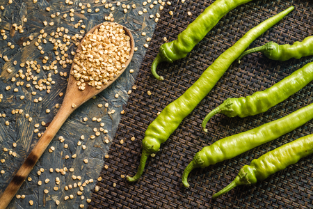 Green peppers on brown fabric sheet and blue background