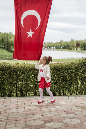 Cute little girl, kissing Turkish flag hanged overの写真素材