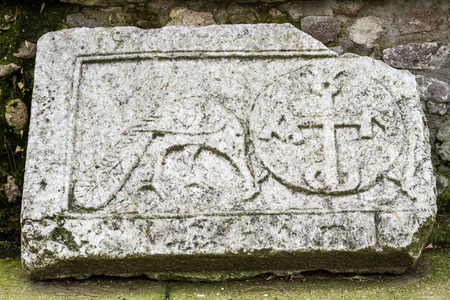 Ancient carved stone leaned on a stone wallの写真素材