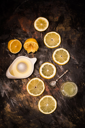 Fresh sliced ripe lemons on plate, with juicer and spoon on blackの写真素材