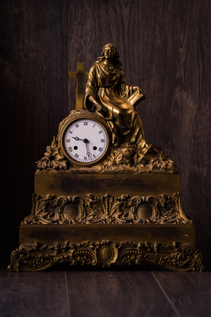 Antique brass metal figural clock on brown background