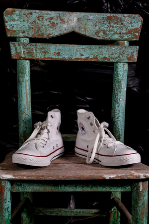 ESKISEHIR, TURKEY - MAY 9, 2010: White Converse sneakers on an old green chair background