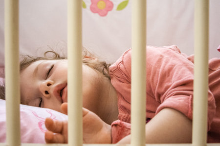 Cute baby girl sliping in wooden crib, natural lookの写真素材