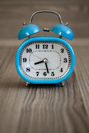 Vintage blue alarm clock on wooden table, classic timepiece design.の写真素材