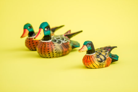 Handmade wooden duck family on a yellow background.の写真素材