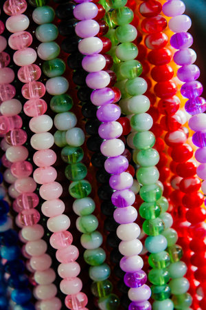 Close up of colorful beaded necklaces in various shades of pink, blue, green, and purple, arranged in rows.の写真素材