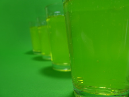 Absinthe liqueur in colored glasses on a green backgroundの写真素材