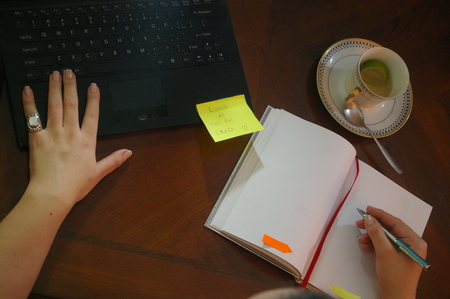 Woman drawing a heart on a notebook on a wood deskの写真素材