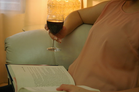 Woman reading a book with a cup of wineの写真素材
