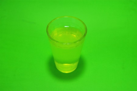 Absinthe liqueur in a transparent glass on a green backgroundの写真素材