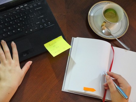 Woman writing in a notebook on her work tableの写真素材