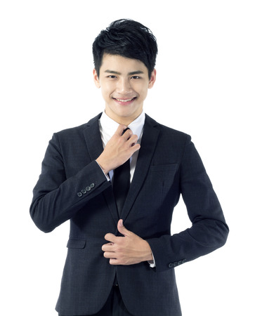 Portrait of young businessman correcting his necktie with smileの写真素材