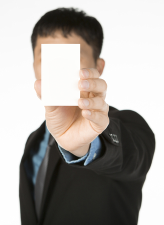 young asian man showing a blank namecard that covers his face, isolated white backgroundの写真素材