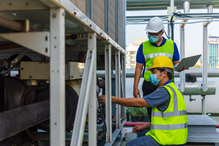 Two Asian engineer using laptop with machine maintainance.の写真素材