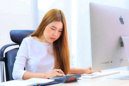 An Asian woman work in office with calculator and computerの写真素材