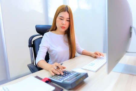 An Asian woman work in office with calculator and computerの写真素材