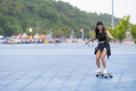 Asian woman playing surf skate or skates board outdoors on beautiful summer day. Happy young women play surf skate at park on morning time in the park.の写真素材