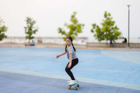Asian girl playing surfskate in the park. sport and recreation concept.の写真素材