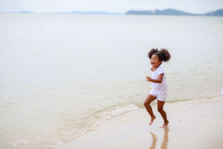 Happy African girl running on the beach.の写真素材