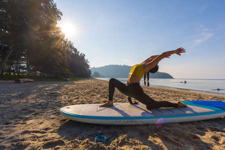 Surfer woman sitting on surfboard on the beach. Healthy lifestyleの写真素材