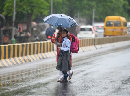 NOIDA, INDIA - JULY 10: Commuters step out during afternoon rain, which brought down the humidity level in the city on July 10, 2024 in Noida, India. Heavy rain in several parts of Delhi, Noida and their adjoining areas in the National Capital Region (NCRのeditorial素材