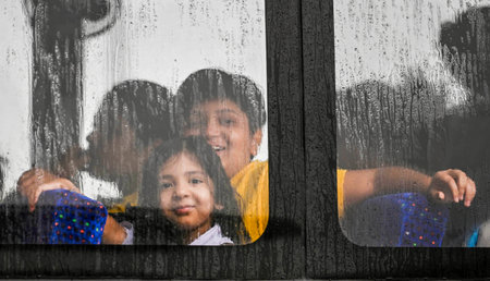 NEW DELHI, INDIA - JULY 10: School Students looks out through the window of the school bus during heavy rain at Mayur Vihar on July 10, 2024 in New Delhi, India. Heavy rain in several parts of Delhi, Noida and their adjoining areas in the National Capitalのeditorial素材