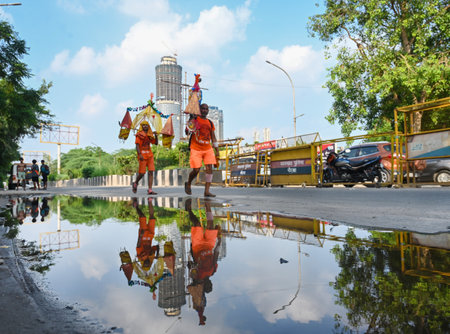 NOIDA, INDIA - JULY 29: Kanwariyas carrying holy water collected from River Ganga in Haridwar going back to their hometown during the Kanwar Yatra on a footpath through the Okhla Barrage on July 29, 2024 in Noida, India. People will celebrate the Sawan Shのeditorial素材