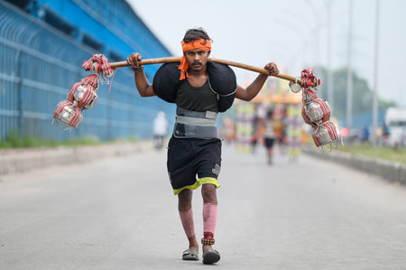 NOIDA, INDIA - JULY 31:  Kanwariyas carrying holy water collected from River Ganga in Haridwar going back to their hometown during the Kanwar Yatra on a footpath through the Okhla Bridge near Kalindi Kunj. People will celebrate the Sawan Shivratri on 02 Aのeditorial素材