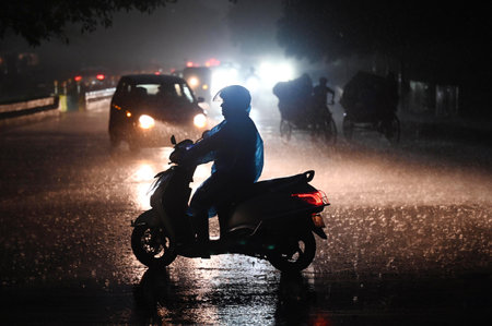 NOIDA, INDIA - JULY 31:  Commuters stepping out during the evening rain after a humid summer, in...