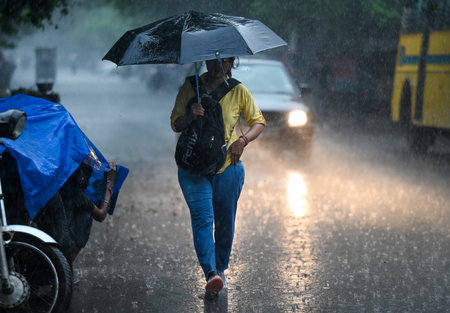 NOIDA, INDIA - SEPTEMBER 5 2024  Commuters step out during afternoon rain at sector 12, on Delhi-NCR residents witnessed a sudden change in weather as heavy rain lashed several parts of the city, on September 5, 2024 in Noida, India. (Photo by Sunil Ghoshのeditorial素材