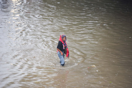 GURUGRAM, INDIA - SEPTEMBER 4 2024  People cross a waterlogged stretch during heavy rain on the NH-48 service road near Narsinghpur village foot-over-bridge, on September 4, 2024 in Gurugram, India. Delhi-NCR residents witnessed a sudden change in weatherのeditorial素材