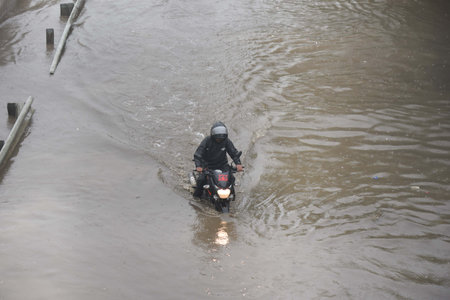 GURUGRAM, INDIA - SEPTEMBER 4 2024  A biker trying to cross a waterlogged stretch during heavy rain on the NH-48 near Narsinghpur village, on September 4, 2024 in Gurugram, India. Delhi-NCR residents witnessed a sudden change in weather as heavy rain lashのeditorial素材