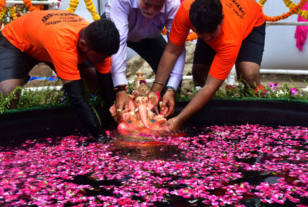 MUMBAI, INDIA - SEPTEMBER 8 2024  A volunteer immerses Lord Ganesha idol in an artificial pond during the one-and-half day Ganpati immersion, at Dadar, on September 8, 2024 in Mumbai, India. (Photo by Bhushan Koyande/Hindustan Times )のeditorial素材