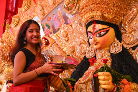 GURUGRAM, INDIA - OCTOBER 13: A woman performs rituals on an idol of Durga Maa during Sindoor Khela on the final day of the Durga Puja Festival organised by Purbapalli Durgotsav at sector-15 part-2 community centre near Huda Market, on October 13, 2024 inのeditorial素材
