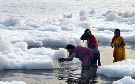 NEW DELHI, INDIA - NOVEMBER 2: Women offering prayer during Toxic foam seen floating over Yamuna River at Kalindi Kunj on November 2, 2024 in New Delhi, India. The Yamuna River is inundated with toxic foam ahead of Chhath Puja, set to be celebrated from Nのeditorial素材