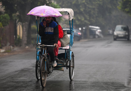 NOIDA INDIA DECEMBER 23 2024 Commuters during light rain in winter in sector 12 rain increased the severe cold in North India on December 23 2024 in Noida India Parts of Delhi-NCR witnessed light rainfall on morning however the scattered showers did not mのeditorial素材